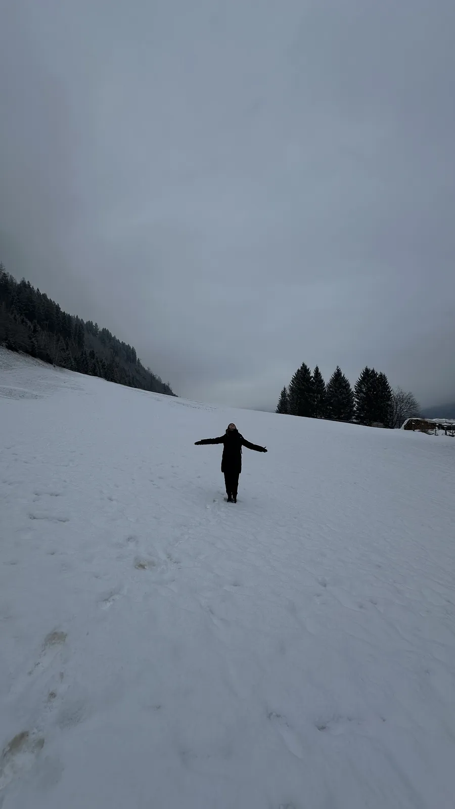 Talita de braços abertos num campo de neve