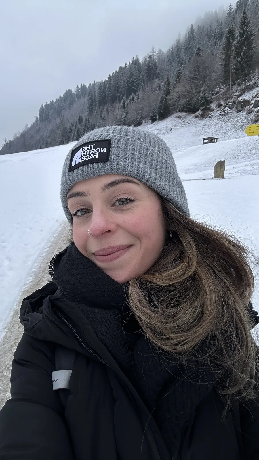 Talita sorrindo de gorro cinza na neve