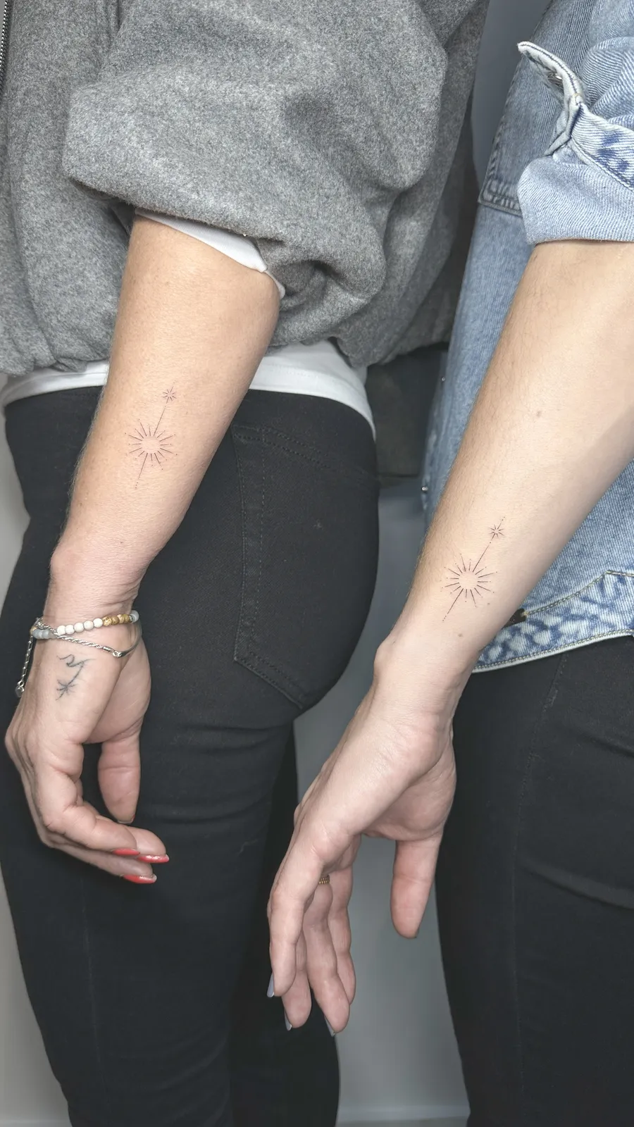 Sóis gêmeos tatuados nos pulsos de duas pessoas