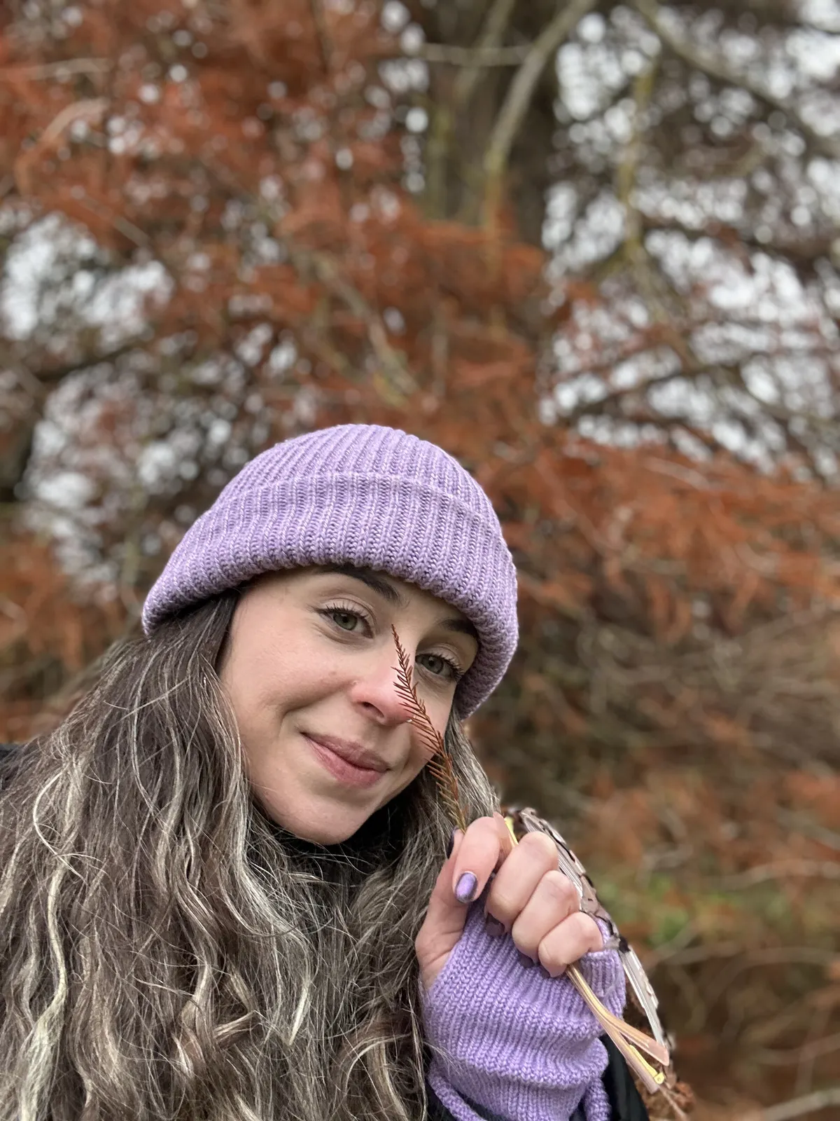 Talita de gorro lilás entre folhas de outono